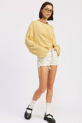 Woman wearing a yellow striped sweater and white shorts on a white background
