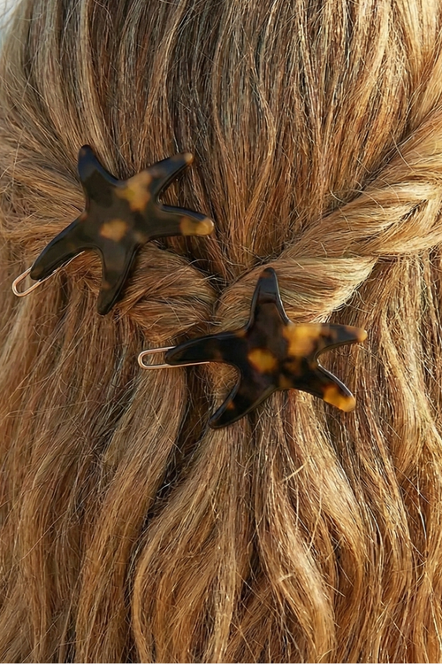 Star-shaped hair clips in a person's braided hair with a beach background