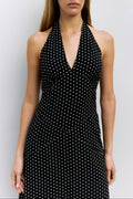 Woman wearing a black dress with white polka dots against a plain background