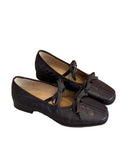 Pair of brown suede shoes with decorative laces on a textured surface