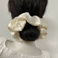 Mannequin head with a white ruffled hair accessory and dark hair on a plain background
