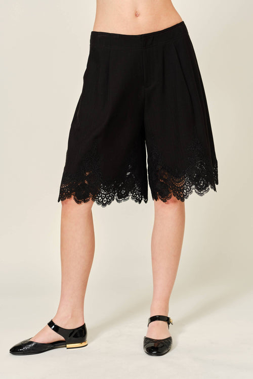 Black lace-trimmed shorts worn by a person on a plain background