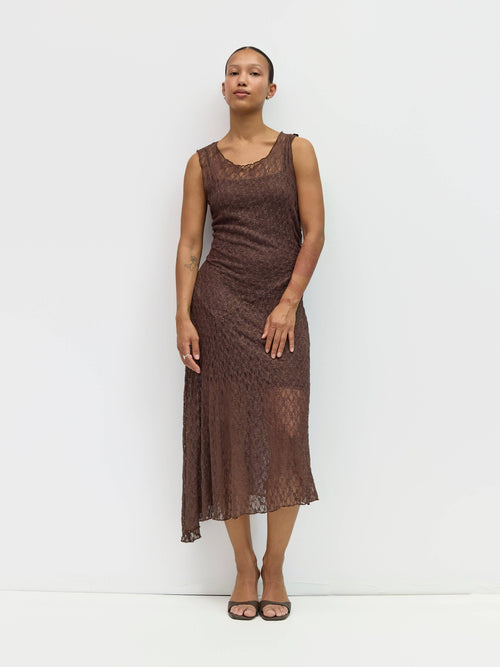 Woman wearing a brown lace dress against a white background