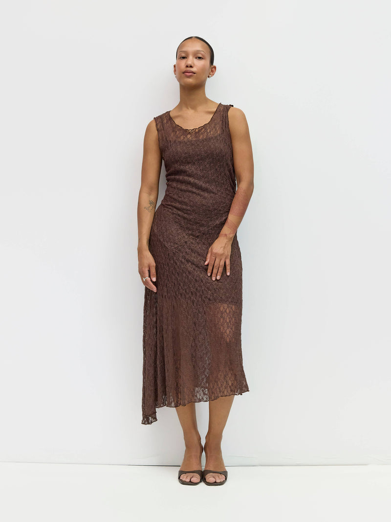 Woman wearing a brown lace dress against a white background
