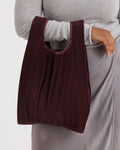 Person holding a brown ribbed handbag against a white background