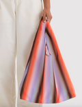 Colorful handbag held by a person against a white background