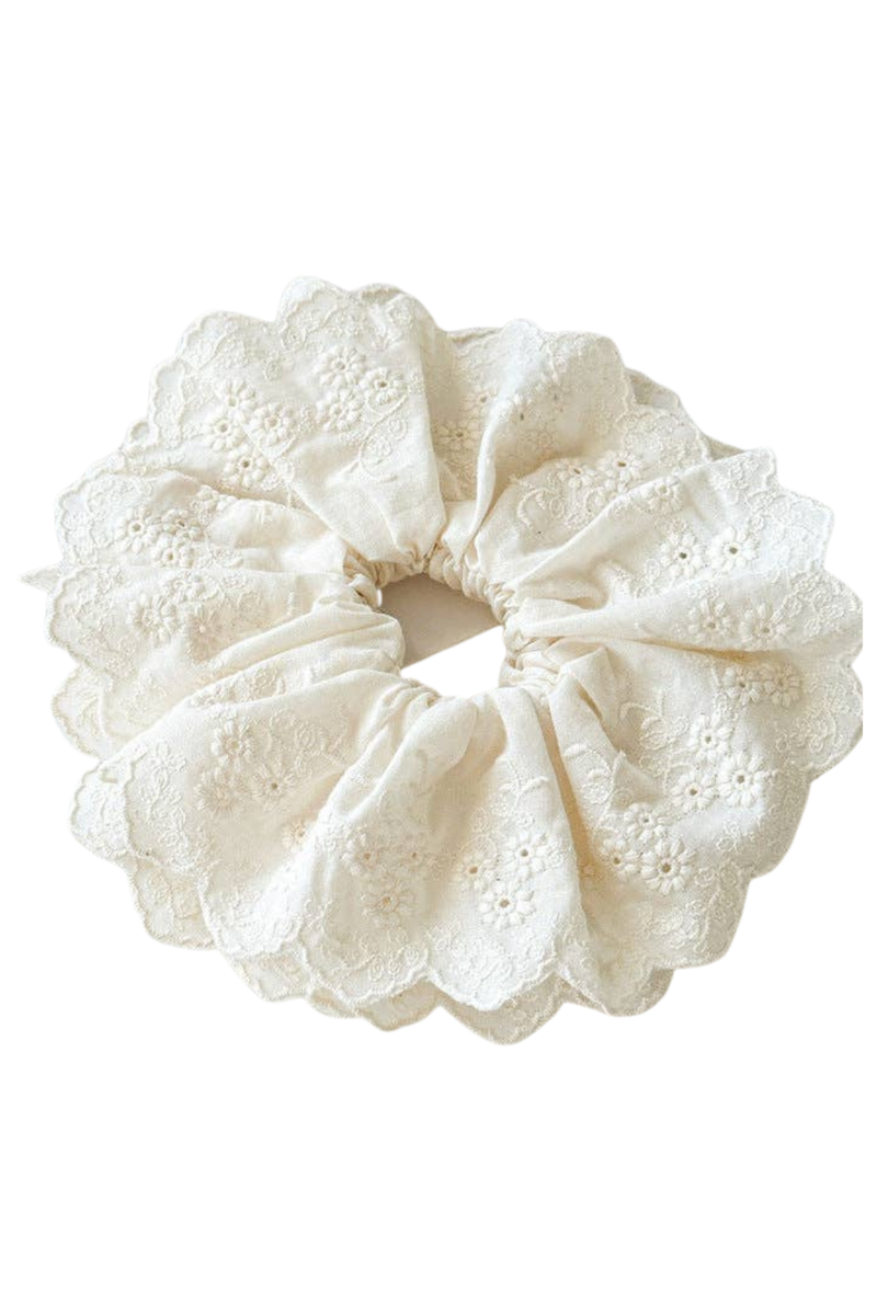 An off-white lace hair scrunchie with delicate eyelet embroidery and scalloped edges, shown against a plain white background.